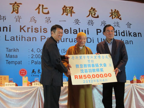 在净空法师的见证下，丹斯里拿督李金友移交五万令吉模拟支票给教总主席王超群。