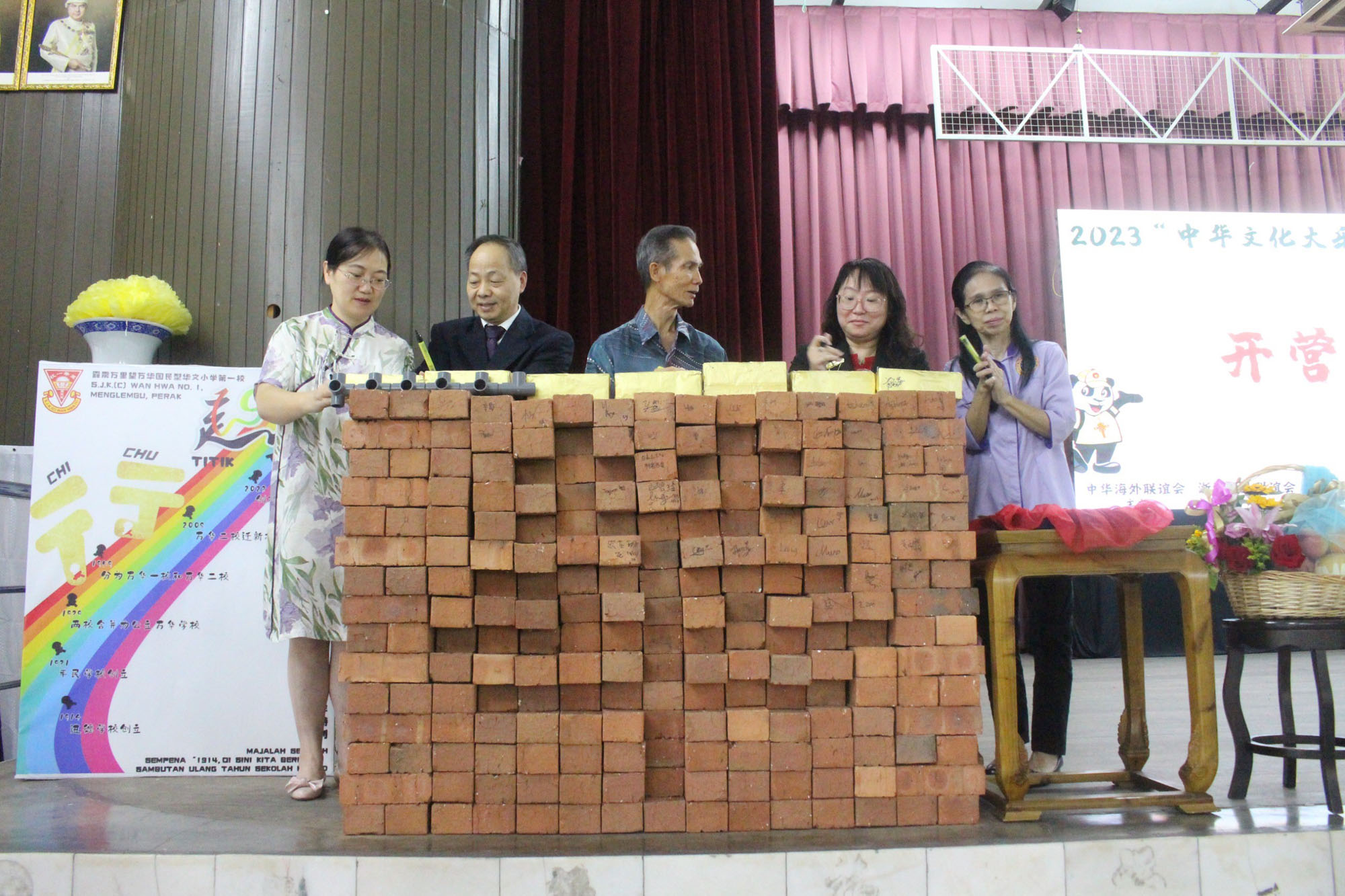 嘉宾们在砖块上签名，这些砖块堆叠成⼀个“华”字，蕴含了中⽅与马来西 亚的华族同胞之间的紧密凝聚之意，也是⼀种凝聚⼒的象征。
